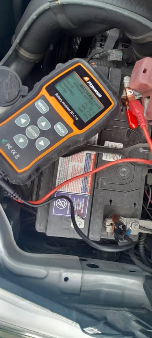 Car battery being tested with a multimeter